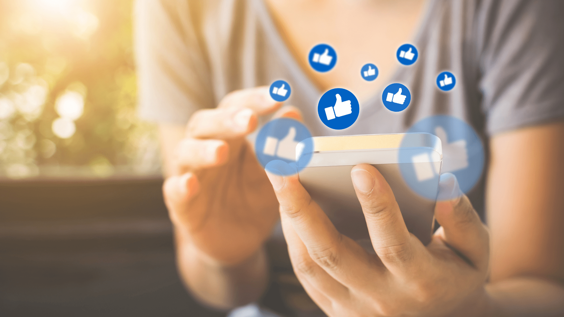 Woman in relaxed tee checks Facebook on smartphone with floating "like" bubbles in front of a sunny window with plants